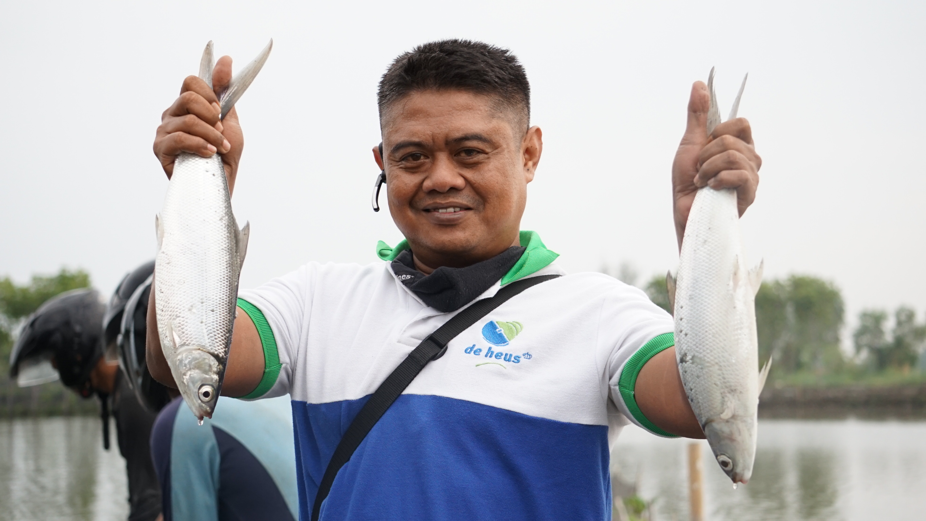 Seorang pembudidaya memegang 2 ekor ikan bandeng