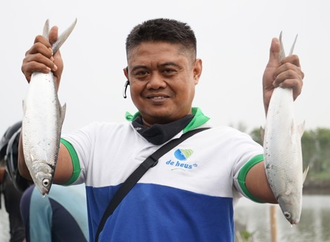 Seorang pembudidaya memegang 2 ekor ikan bandeng