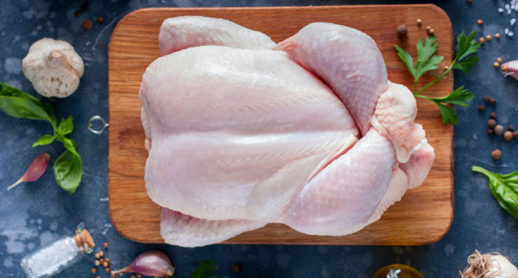 Karkas ayam segar yang ditempatkan diatas sebuah talenan kayu
