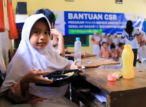 Seorang anak yang sedang memegang menu makan siang bergizi yang disediakan De Heus Indonesia untuk mendukung program pemerintah