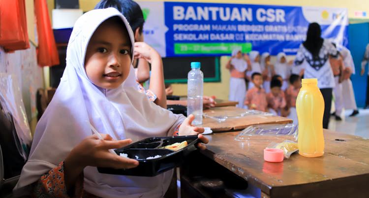 Seorang anak yang sedang memegang menu makan siang bergizi yang disediakan De Heus Indonesia untuk mendukung program pemerintah